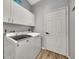 Efficient laundry room with white cabinets, modern appliances, and wood look flooring at 10922 Holly Cone Dr, Riverview, FL 33569