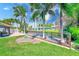 Grassy backyard featuring a patio, deck, palm trees, and waterfront canal at 11035 Huron Rd, St Petersburg, FL 33708