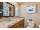 Bathroom featuring granite counters, wood cabinets, tiled walls, and a framed mirror with good natural light at 11035 Huron Rd, St Petersburg, FL 33708