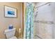 Shower featuring tiled walls with a shower caddy, mosaic accent border, and a green patterned shower curtain at 11035 Huron Rd, St Petersburg, FL 33708