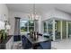 Dining room with a large table, modern chandelier, and sliding glass doors to the outdoor patio at 11432 Shoreline Trl, Parrish, FL 34219