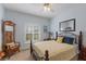 Bright bedroom featuring blue walls, a ceiling fan, shuttered windows, and a comfortable bed with accent pillows at 12345 Citrus Way, Brooksville, FL 34601