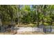 A gated driveway leads into a property with a lush lawn and wooded area beyond at 12345 Citrus Way, Brooksville, FL 34601