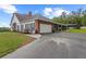 Rear of the house with an attached garage, screened porch, brick accents, and a paved driveway at 12345 Citrus Way, Brooksville, FL 34601