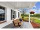 Inviting covered porch with a hanging wooden swing, stylish columns, and lush landscaping at 12345 Citrus Way, Brooksville, FL 34601