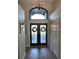 Inviting entryway with wood floor, double doors with wreaths and transom window with a modern light fixture at 1310 Country Trails Dr, Safety Harbor, FL 34695