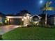 Beautifully landscaped home featuring a well-manicured lawn and elegant exterior lighting at 1310 Country Trails Dr, Safety Harbor, FL 34695