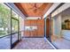 Screened in lanai with wood ceiling, ceiling fan, brick flooring, wooden cabinets, and lake views at 1324 Eckles Dr, Tampa, FL 33612