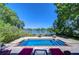 In-ground pool with patio, lounge chairs, lush landscaping, and lake views creating an outdoor oasis at 1324 Eckles Dr, Tampa, FL 33612