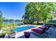 Backyard pool area with brick patio, lounge chairs, lush landscaping, and beautiful lake views at 1324 Eckles Dr, Tampa, FL 33612