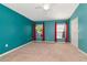Spacious bedroom featuring neutral carpeting, turquoise walls, and two bright windows with red curtains at 1505 Trailwater St, Ruskin, FL 33570