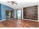 Open living room with hardwood floors, brick accent wall, and sliding glass doors to the screened patio at 1505 Trailwater St, Ruskin, FL 33570