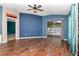 Bright living room boasts hardwood floors, blue accent wall, sliding glass doors and ceiling fan at 1505 Trailwater St, Ruskin, FL 33570
