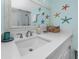 This updated bathroom features a stylish vanity with a white countertop, decorative starfish, and a modern mirror at 159 Medallion Blvd # H, Madeira Beach, FL 33708