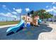 Community playground with a blue slide, wooden fort, and safety-first cushioned flooring at 159 Medallion Blvd # H, Madeira Beach, FL 33708
