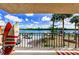 Relaxing balcony with surfboards overlooking a canal with boat dock, palm trees, and vehicles at 18201 Gulf Blvd # 201, Redington Shores, FL 33708