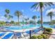 Resort-style community pool with lounge chairs, umbrellas, water park, and lush landscaping on a sunny day at 22223 Storybook Cabin Way, Land O Lakes, FL 34637