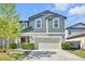 Charming two-story home with blue siding, manicured landscaping, and a welcoming red front door at 22223 Storybook Cabin Way, Land O Lakes, FL 34637