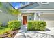Inviting front entrance featuring a vibrant red door, trimmed shrubbery, and manicured green lawn at 22223 Storybook Cabin Way, Land O Lakes, FL 34637