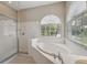 Bright main bathroom featuring a soaking tub with windows and a glass shower at 2816 Pankaw Ln, Valrico, FL 33596