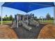 Large playground with multiple slides and climbing structures under a blue shade at 31440 Barrel Wave Way, Wesley Chapel, FL 33545
