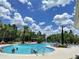 Large community pool with ample seating, landscaping, and blue skies with fluffy white clouds at 33034 Sand Creek Dr, Wesley Chapel, FL 33543