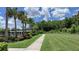 Community walking path alongside manicured lawn and landscaping with palms against a partially cloudy blue sky at 33034 Sand Creek Dr, Wesley Chapel, FL 33543
