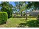Green backyard featuring a wooden fence, lush landscaping, and a glimpse of a screened patio in a serene setting at 4769 Stoneview Cir, Oldsmar, FL 34677