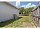 Side view of the backyard featuring a wooden fence, the back of the house, and scattered vegetation at 4816 E 99Th Ave, Tampa, FL 33617
