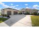 Spacious home featuring a large driveway, three-car garage, stone accents, and manicured landscaping at 5325 San Remo Cir, Wimauma, FL 33598