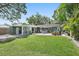 Expansive backyard with lush lawn, mature trees, patio, hot tub, and covered parking area at 6213 10Th S Ave, Gulfport, FL 33707