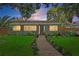 Charming home exterior with a lush lawn, mature trees, and a brick walkway at 6213 10Th S Ave, Gulfport, FL 33707