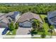 Aerial view of home showcasing a well-maintained property, three-car garage, landscaping, and a paver driveway at 6307 Salt Creek Ave, Apollo Beach, FL 33572
