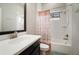 Bright bathroom with white tiling, shower-tub combo, modern black vanity and warm-toned shower curtain at 6307 Salt Creek Ave, Apollo Beach, FL 33572
