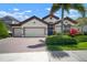Charming home featuring a three car garage, lush landscaping, and an inviting blue front door at 6307 Salt Creek Ave, Apollo Beach, FL 33572