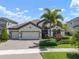 Charming single-Gathering home with a three-car garage, paver driveway, and mature landscaping with a palm tree at 6307 Salt Creek Ave, Apollo Beach, FL 33572