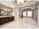 This bathroom features a sunken tub, walk-in shower, marble floors, decorative columns and dark wood vanities at 6408 Bright Bay Ct, Apollo Beach, FL 33572