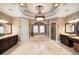 A luxurious bathroom with marble floors, dark wood vanities, decorative columns, and a decorative ceiling at 6408 Bright Bay Ct, Apollo Beach, FL 33572