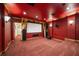 Red home theater with tiered seating, projector screen, and sconce lighting at 6408 Bright Bay Ct, Apollo Beach, FL 33572