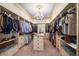 Spacious walk-in closet with custom shelving, central island, bench seating and elegant chandelier lighting at 6408 Bright Bay Ct, Apollo Beach, FL 33572