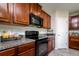 Well-lit kitchen features granite countertops, wood cabinetry, and modern black appliances at 6534 Trent Creek Dr, Ruskin, FL 33573