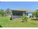 A view of the back of this house with a screened-in lanai overlooking a green lawn with manicured landscaping at 7413 Surrey Wood Ln, Apollo Beach, FL 33572