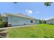 Side view of a light blue single-story home with a green lawn and a glimpse of a screened-in patio at 7413 Surrey Wood Ln, Apollo Beach, FL 33572