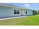 Side view of a light blue single-story home with a green lawn and a screened-in patio visible at 7413 Surrey Wood Ln, Apollo Beach, FL 33572