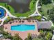 Aerial shot of an inviting outdoor pool surrounded by tables, palm trees, and well-manicured landscaping at 7413 Surrey Wood Ln, Apollo Beach, FL 33572