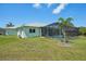 Expansive backyard featuring a screened-in pool, lush lawn, and tropical landscaping at 7504 Carissa, Punta Gorda, FL 33955