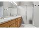 Well-lit bathroom with dual sinks, wood cabinets and a shower with glass sliding doors at 7725 Bingham Ct, Tampa, FL 33625