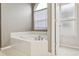 Bathroom featuring a large tiled soaking tub and natural light from the window at 7725 Bingham Ct, Tampa, FL 33625