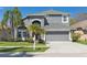 Charming two-story home featuring a manicured lawn, gray facade, arched entryway, and a two-car garage at 7725 Bingham Ct, Tampa, FL 33625