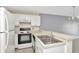 Close-up of kitchen with white cabinets, white appliances, and stainless steel sink at 8013 Savannah Sunset Ln, Tampa, FL 33615